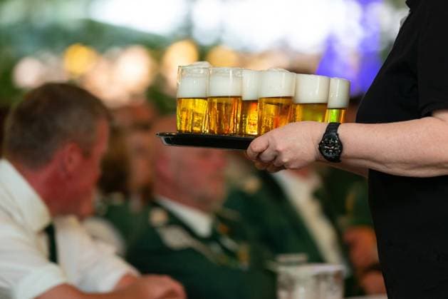 Bohmte, Deutschland 03. Juni 2022: Ein Kellner trägt auf einem Schützenfest ein Tablet mit Bier. Im Hintergrund sieht man Menschen an Tischen sitzen. Landkreis Osnabrück Niedersachsen *** Bohmte, Germany 03 June 2022 A waiter carries a tray with beer at a shooting festival In the background you can see people sitting at tables County Osnabrück Lower Saxony Copyright: xFotostandx xGelhotx