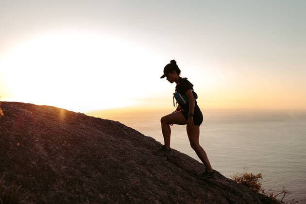 Creative Highlights Symbolbilder Side view of sportswoman climbing up on hill against sunset Copyright: xArtemxVarnitsinxArtemxVarnitsinx