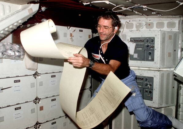 (12-14 Nov. 1981) --- Astronaut Richard H. Truly, STS-2 pilot, peruses some teleprinter copy, floating partially about the middeck area of NASA™s space shuttle Columbia during one of 1,813 minutes of activity of STS-2. This photograph was recorded with 35mm camera in the hands of astronaut Joe H. Engle, STS-2 crew commander. Truly communicates with spacecraft communicators on the ground. Photo : NASA 1062_36_M_-11400-