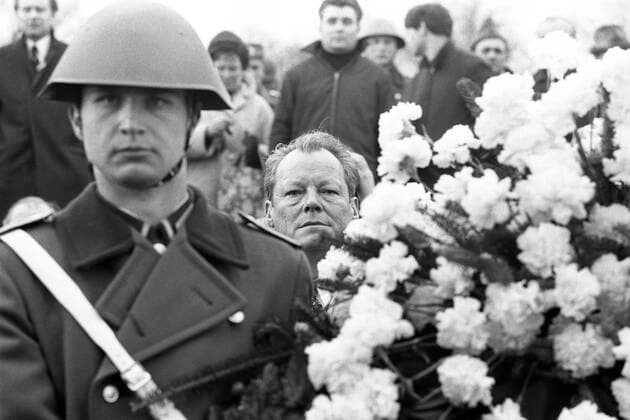 Bundeskanzler Willy BRANDT schaut zwischen einem NVA Soldaten und einem Blumengesteckt hindurch, bei der Kranzniederlegung im ehemaligen Konzentrationslager Buchenwald, anlaesslich eines Treffens mit DDR Ministerpraesident Willi Stoph am 19.03.1970 in Erfurt; Schwarzweissaufnahme; *** Federal Chancellor Willy BRANDT looks between a NVA soldier and a flower arrangement through, with the wreath-laying in the former concentration camp Buchenwald, on the occasion of a meeting with GDR Prime Minister Willi Stoph on 19 03 1970 in Erfurt black and white photo