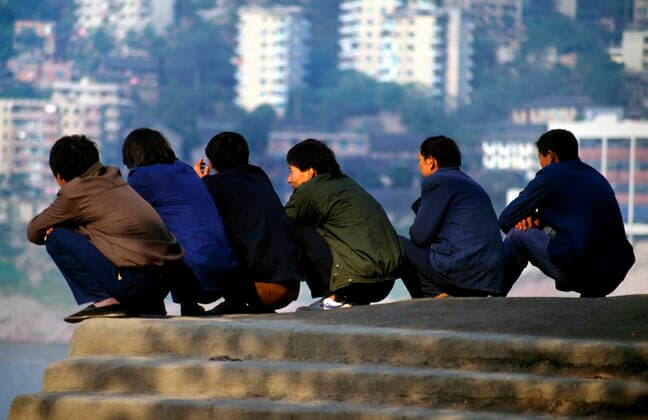 Chongqing, Sichuan, China - December 1997 Itinerant migrant working hanging and waiting for hire used to be one of China s major social problems during this period. Here we see such a group squatting and chatting by the banks of the YangTse River at Chongqing, a huge megacity in Sichuan Province of China. JonxBowerxatxApexphotos 4053_19_POI_L_CHONGQING_000012