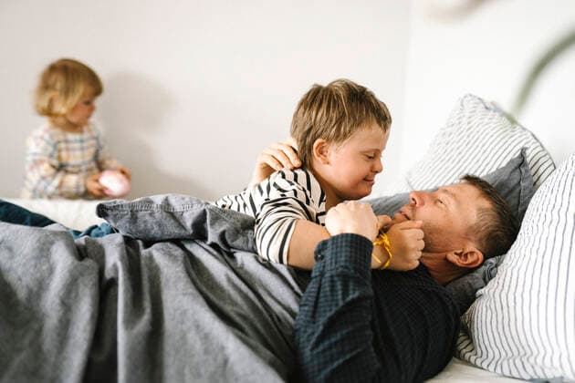 Son having down syndrome with father lying on bed in bedroom at home Sweden, Gothenburg, model released, property released Copyright: xMaskotx , MA93772