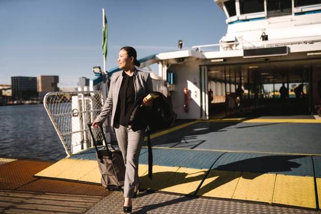 IMAGO Creative: Neue Aussichten Businesswoman pulling wheeled luggage while disembarking from ferry on sunny day Sweden, Gothenburg, model released Copyright: xMaskotx , MA94036
