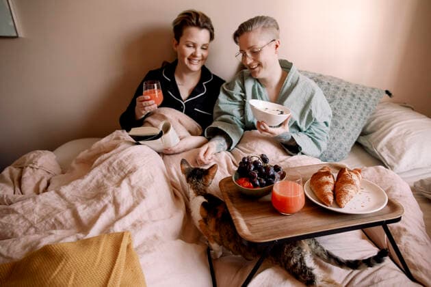 Smiling lesbian couple having breakfast in bed with cat at home Sweden, Stockholm, model released, property released Copyright: xMaskotx , MA94146