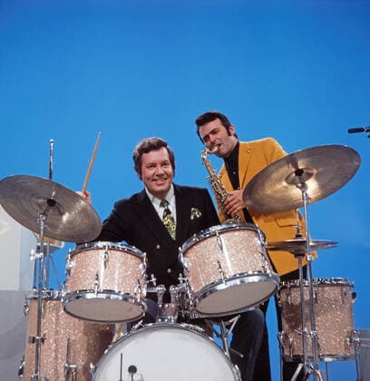DREI MAL NEUN Drei mal Neun, ZDF Quizshow, Deutschland, 1971, im Bild: Showmaster Wim Thoelke, hier am Schlagzeug mit Bandleader Max Greger am Saxophon. Drei mal Neun, TV quiz show, Germany, 1971, on the photo: presenter Wim Thoelke, here on the drums with Band leader Max Greger on saxophone., Deutschland Copyright: ArthurxGrimm UnitedArchives82007921 EDITORIAL USE ONLY