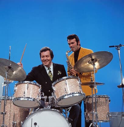 DREI MAL NEUN Drei mal Neun, ZDF Quizshow, Deutschland, 1971, im Bild: Showmaster Wim Thoelke, hier am Schlagzeug mit Bandleader Max Greger am Saxophon. Drei mal Neun, TV quiz show, Germany, 1971, on the photo: presenter Wim Thoelke, here on the drums with Band leader Max Greger on saxophone., Deutschland Copyright: ArthurxGrimm UnitedArchives82007922 EDITORIAL USE ONLY