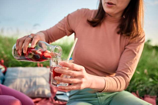 Young woman pouring infused water in glass at field on weekend model released, Symbolfoto, ZEDF04562