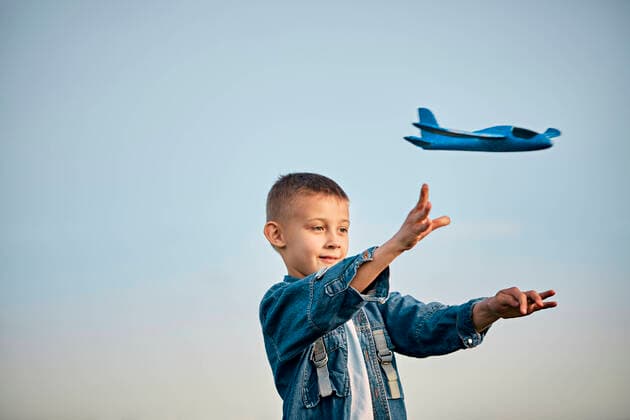 Creative Highlights Symbolbilder Boy playing with blue toy airplane in front of sky at sunset model released, Symbolfoto, ZEDF04569