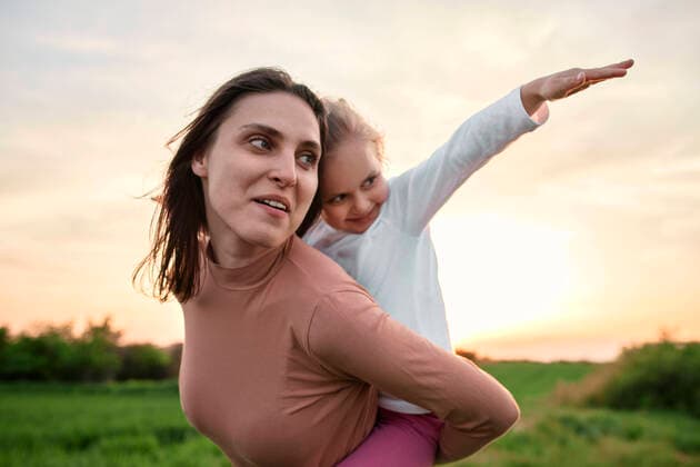 Creative Highlights Symbolbilder Smiling woman carrying daughter piggyback on weekend model released, Symbolfoto, ZEDF04632