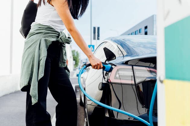 IMAGO Creative: Neue Aussichten Woman with electric plug charging car at vehicle station model released, Symbolfoto, MEUF05949