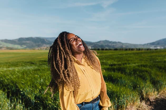 Creative Highlights Symbolbilder Young woman with curly hair laughing in meadow on sunny day model released, Symbolfoto, DMGF00723