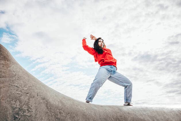 Creative Highlights Symbolbilder Woman with arms raised dancing under cloudy sky model released, Symbolfoto, OMIF00886