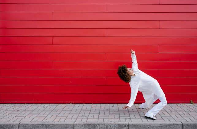 IMAGO Creative: 2022 Favoriten Woman dancing on footpath by red wall model released, Symbolfoto, GIOF15518