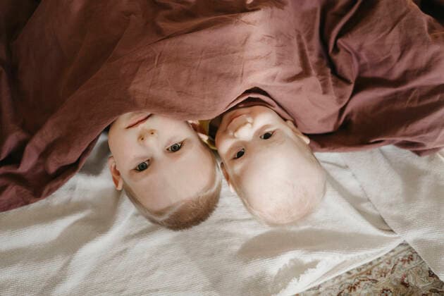 Creative Highlights Symbolbilder Cute boys lying under blanket on bed at home model released, Symbolfoto property released, SEAF00939