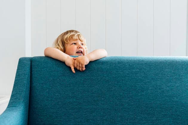 Creative Highlights Symbolbilder Cute boy standing behind sofa in living room at home model released, Symbolfoto property released, VPIF06294