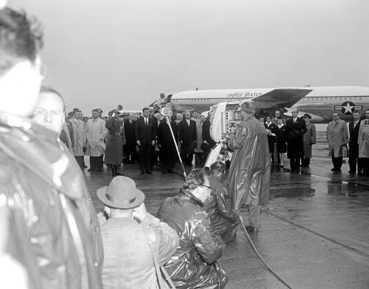 Trip to Europe: Arrival in Vienna, Austria 10:50AM; White House Army Signal Agency (WHASA) staff in Vienna. President John F. Kennedy and President of Austria Adolf Schärf upon President Kennedys arrival at Schwechat Airport in Schwechat, Austria; the President visited Vienna for a summit with Soviet Union Premier Nikita Khrushchev. Also included in the photograph are White House Secret Service Agent James Rowley, Naval Aide to the President Commander Tazewell T. Shepard, members of the Austrian government, and members of the press. Air Force One is visible in the background. Copyright: xpiemagsx