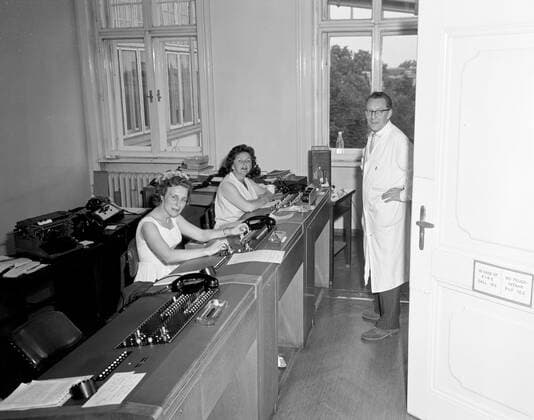 Trip to Europe: Arrival in Vienna, Austria 10:50AM; White House Army Signal Agency (WHASA) staff in Vienna. Three unidentified White House Army Signal Agency (WHASA) staff members (two women sitting behind communications equipment and one man standing) prepare for a summit between President John F. Kennedy and Soviet Union Premier Nikita Khrushchev in Vienna, Austria. Copyright: xpiemagsx