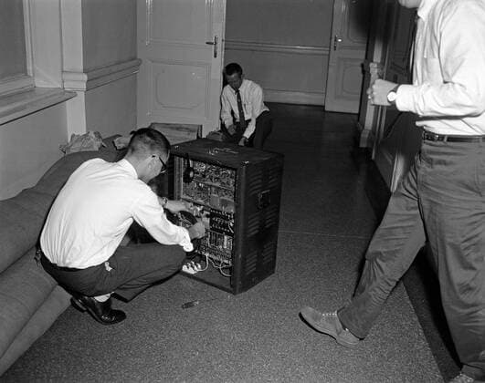 Trip to Europe: Arrival in Vienna, Austria 10:50AM; White House Army Signal Agency (WHASA) staff in Vienna. Three unidentified men (two kneeling and one standing) prepare White House Army Signal Agency (WHASA) equipment for a summit between President John F. Kennedy and Soviet Union Premier Nikita Khrushchev in Vienna, Austria. Copyright: xpiemagsx