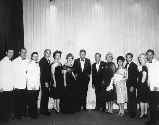 White House News Photographers Association (WHNPA) Dinner, 7:37PM. President John F. Kennedy poses with performers at the White House News Photographers Association (WHNPA) dinner. L-R: five unidentified persons; actress, Shelley Winters; President Kennedy; comedian and Master of Ceremonies, Alan King; singer, Jane Morgan; dancers, Margo Rodr u1f77guez and Augie Rodr u1f77guez; unidentified; musician, Chet Atkins. Sheraton Park Hotel, Washington, D.C. Copyright: xpiemagsx