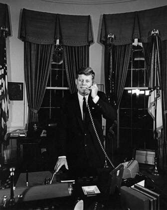 President Kennedy telephones Astronaut Gordon Cooper aboard USS Kearsarge (CVS-33), after recovery of Faith 7. President John F. Kennedy (standing at his desk) speaks on the telephone with astronaut, Major L. Gordon Cooper, following the successful completion of Major Coopers Mercury-Atlas 9 orbital flight, as part of the final manned space mission of the National Aeronautics and Space Administrations (NASA) Project Mercury program. Major Cooper was aboard the USS Kearsarge (CVS-33) after splashdown and recovery of the Mercury capsule (also known as Faith 7) in the Pacific Ocean. Oval Office, White House, Washington, D.C. Copyright: xpiemagsx