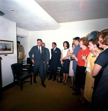 Surprise birthday party for President Kennedy, given by the White House staff, 5:45PM. President John F. Kennedy arrives at a surprise party thrown by members of the White House staff in honor of his 46th birthday. Left to right: Naval Aide to the President, Captain Tazewell Shepard (in doorway, face hidden); President Kennedy; White House Secret Service agents, John J. Muggsy O Leary (partially hidden) and Clint Hill; First Lady Jacqueline Kennedy; First Lady s Social Secretary, Nancy Tuckerman; four unidentified persons. Navy Mess Hall, White House, Washington, D.C. Copyright: xpiemagsx