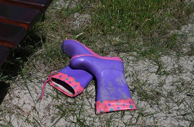 Kindergummistiefel neben einer Bank, aufgenommen auf Spiekeroog, Niedersachsen, am 15. Juni 2022. *** Childrens rubber boots next to a bench, taken on Spiekeroog, Lower Saxony, on 15 June 2022