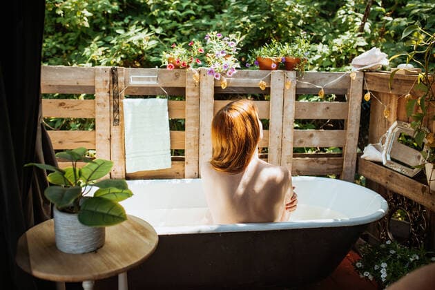 Creative Highlights Symbolbilder Back view of faceless topless thoughtful redhead female sitting in bathtub near wooden fence on patio during skin care routine on summer day, Model released CamilleGirard_WomanOnPatio_00069.jpg Copyright: xCamillexGirardx MR
