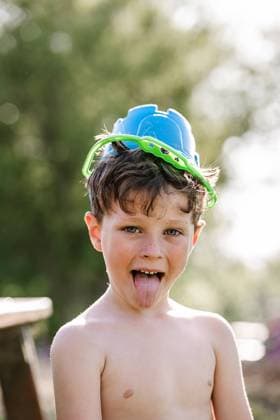 Creative Highlights Symbolbilder Boy with curly hair and a bucket on head sticking tongue and looking at camera in park on sunny day, Model released HodeiUnzueta_HotSummer_00003.jpg Copyright: xHodeixUnzuetax MR