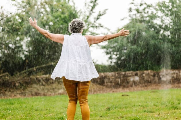 Creative Highlights Symbolbilder Back view of unrecognizable female dancing with spread arms in rain on grassy lawn in countryside with trees on summer day, Model released HodeiUnzueta_WeddingDay_21.jpg Copyright: xHodeixUnzuetax MR