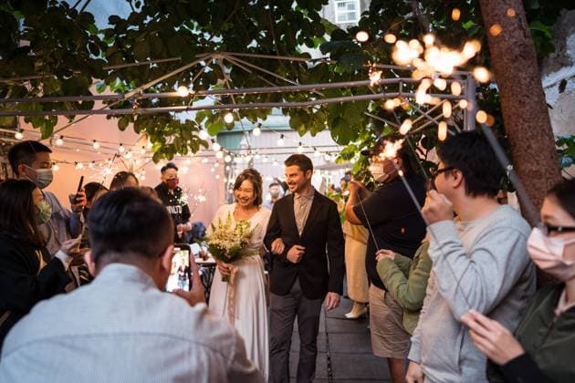 Group of people with lit sparklers congratulating bride and groom during wedding celebration on street decorated with lightbulb garlands JuanAlbertoRuiz_WeddingParty_11.jpg Copyright: xJuanxAlbertoxRuizx Model Released