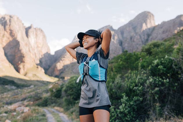 Creative Highlights Symbolbilder Laughing woman in sportswear relaxing during hike. Smiling female in wild terrain looking away. Copyright: xArtemxVarnitsinxArtemxVarnitsinx