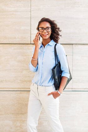 Creative Highlights Symbolbilder Smiling woman making phone call while standing at wall Copyright: xArtemxVarnitsinxArtemxVarnitsinx