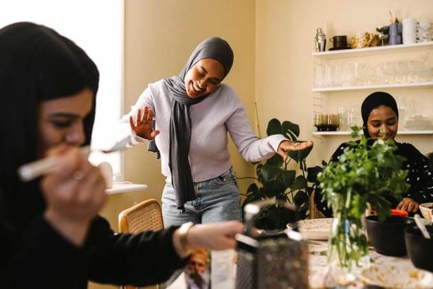 Happy young woman dancing while female friends preparing food at table in kitchen Sweden, Gothenburg, model released, property released Copyright: xMaskotx , MA93287 MA93287