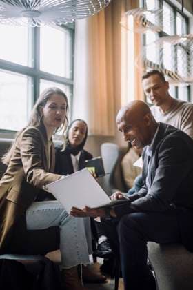 IMAGO Creative: Business, Innovative Technologie-Lösungen Mid adult businesswoman discussing over laptop with bald businessman by colleagues in creative office Sweden, Stockholm, model released, property released Copyright: xMaskotx , MA94335 MA94335