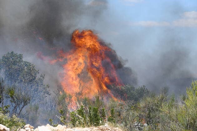 PXL_A fire near Vodice, Croatia Fire in an open area near the Velika Mrdakovica archaeological site in the Vodice hinterland, Croatia on July 13, 2022. About 30 firefighters with a dozen vehicles are on the ground, and two Canadairs joined the ground forces in extinguishing the fire. There are pine forests above, low vegetation, and endangered buildings. HrvojexJelavic PIXSELL