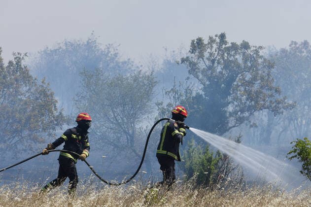 PXL_A fire near Vodice, Croatia Fire in an open area near the Velika Mrdakovica archaeological site in the Vodice hinterland, Croatia on July 13, 2022. About 30 firefighters with a dozen vehicles are on the ground, and two Canadairs joined the ground forces in extinguishing the fire. There are pine forests above, low vegetation, and endangered buildings. HrvojexJelavic PIXSELL
