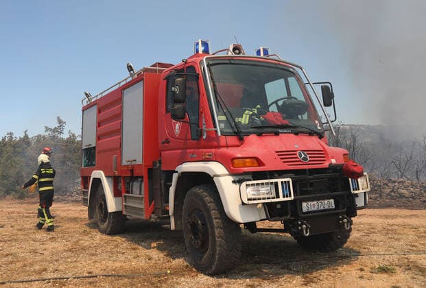 PXL_A fire near Vodice, Croatia Fire in an open area near the Velika Mrdakovica archaeological site in the Vodice hinterland, Croatia on July 13, 2022. About 30 firefighters with a dozen vehicles are on the ground, and two Canadairs joined the ground forces in extinguishing the fire. There are pine forests above, low vegetation, and endangered buildings. DuskoxJaramaz PIXSELL