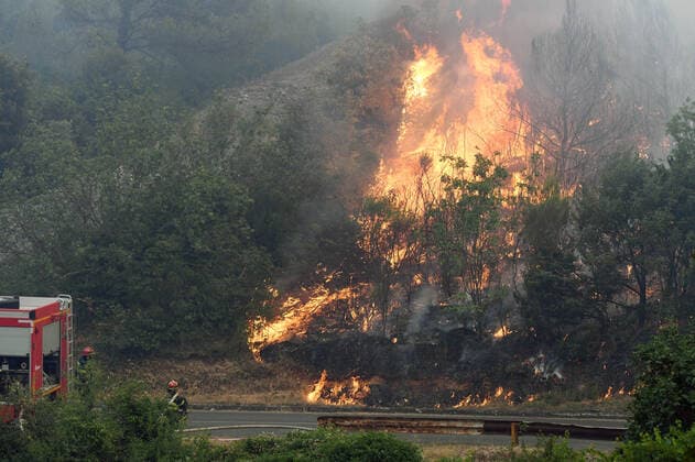 PXL_Zaton fire by the road Fire in an open area near the Zaton site in the Vodice hinterland, Croatia on July 13, 2022. About 30 firefighters with a dozen vehicles are on the ground, and two Canadairs joined the ground forces in extinguishing the fire. There are pine forests above, low vegetation, and endangered buildings. HrvojexJelavic PIXSELL
