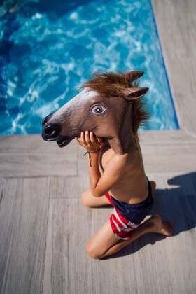 Creative Highlights Symbolbilder Funny child with horse costume mask in swimming pool El Boalo, Community of Madrid, Spain CR_OSCA220706-1006313-01 ,model released, Symbolfoto