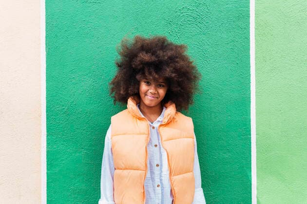Smiling girl with Afro hairstyle standing in front of green wall model released, Symbolfoto, PNAF04012