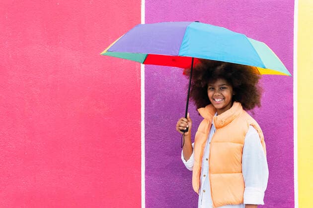 Smiling girl holding multi color umbrella in front of wall model released, Symbolfoto, PNAF04031