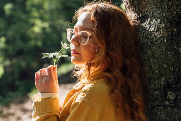 IMAGO Creative: Gesundheit, Stille Woman with eyes closed smelling small flower in forest model released, Symbolfoto, VPIF06534