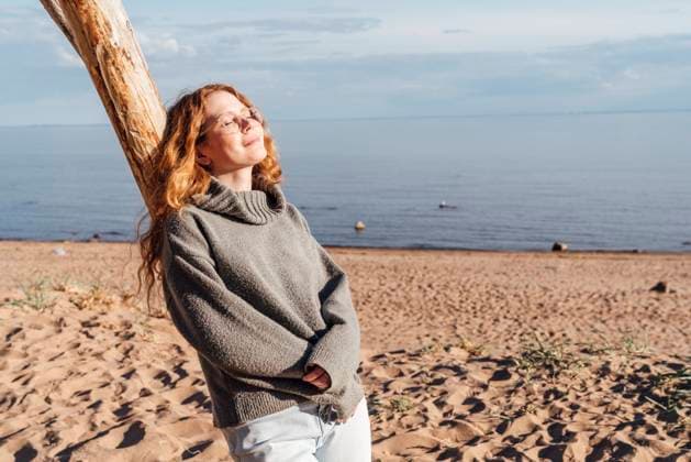IMAGO Creative: Gesundheit, Stille Young woman enjoying sunlight leaning on tree at beach model released, Symbolfoto, VPIF06562