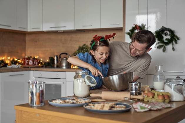 Happy girl mixing cookie dough standing by father in kitchen model released, Symbolfoto property released, ABIF01762
