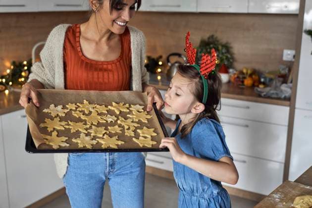 Girl looking at unbaked cookie on pan holding by mother in kitchen model released, Symbolfoto property released, ABIF01776