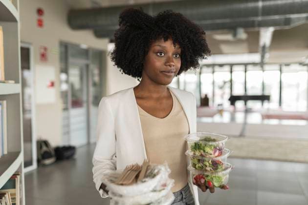 Young businesswoman with salad boxes standing in office model released, Symbolfoto property released, JCICF00173