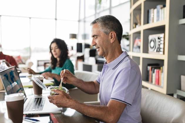 Happy businessman eating salad at desk in office model released, Symbolfoto property released, JCICF00188
