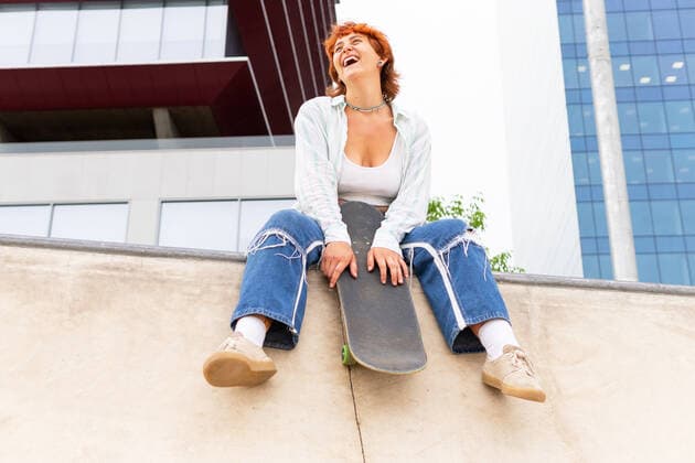 IMAGO Creative: Sommer, Sommertage im Stadtpark Full body of content female in casual wear with skateboard looking away while sitting on concrete border with skate park in city, Model released DavidMunoz_NatiAndHugoSkaters_00017.jpg Copyright: xDavidxMunozx MR