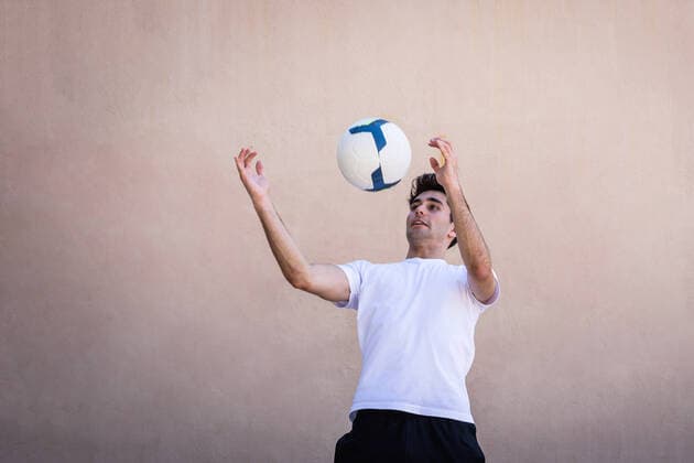 IMAGO Creative: 2022 Sport Favoriten Creative Highlights Symbolbilder Young male football player practicing against beige wall, Model released HarryRendon_FootbalPlayer_20.jpg Copyright: xHarryxRendonx MR