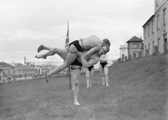 Poll photo collection. Iceland. Reykjavik. Icelandic wrestling (Glima). Two members of the Glimateam of the Menntaskolinn in Aktie. The other team members, one with a banner, look. 1934. Iceland, Reykjavik Copyright: xpiemagsx pienatarchpart630102021-18607 !ACHTUNG AUFNAHMEDATUM GESCHÄTZT!